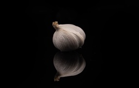 White garlic reflected in a black mirror surface
