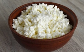 Wooden bowl with cottage cheese on the table
