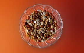 Разные орехи в стеклянной посуде на оранжевом фоне