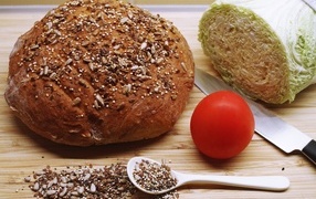 Буханка хлеба на столе с капустой и помидором