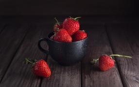 Черная чашка с красными ягодами клубники