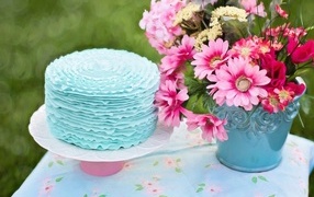 Торт с голубым кремом на столе с цветами