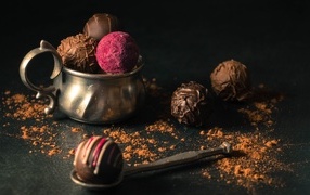 Шоколадные конфеты с железной чашкой на черном фоне