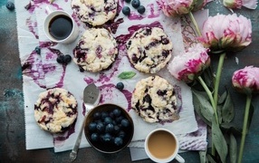 Cookies with blueberries on a table with flowers and coffee