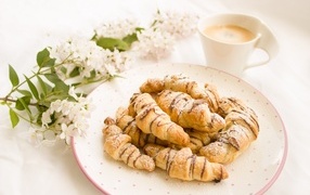Croissants on the table with coffee and flowers