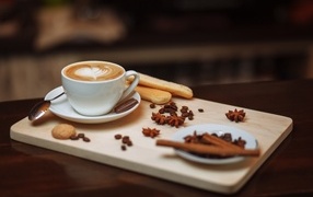 Чашка кофе на доске с печеньем и специями