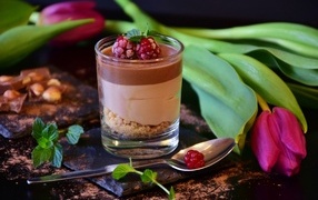 Десерт в стакане на столе с тюльпаном