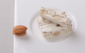 Десерт нуга с миндальными орехами на тарелке 