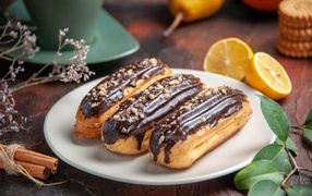 Eclairs on a plate with cinnamon and oranges