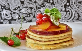 Fritters on a plate with currants and plums