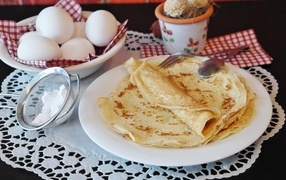 Pancakes on the table with eggs and powdered sugar