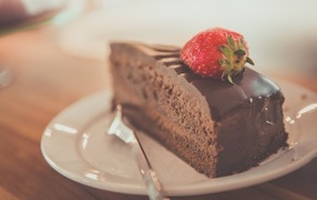 Кусок шоколадного торта с клубникой на тарелке
