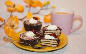 Сладкие вкусные пирожные на столе с чашкой чая и цветами