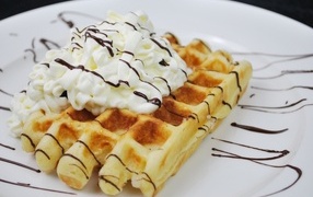 Sweet waffle with cream on a white plate