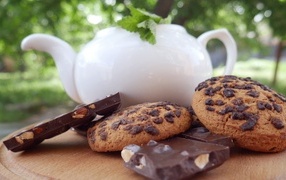 Чайник на столе с печеньем и шоколадом