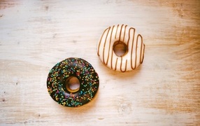 Two glazed donuts on a wooden table