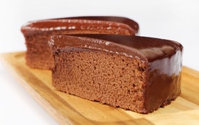 Two pieces of cake with chocolate on a wooden board