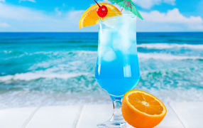 Blue cocktail with ice and half an orange