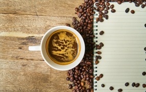 Cup of coffee on the table with beans and notepad