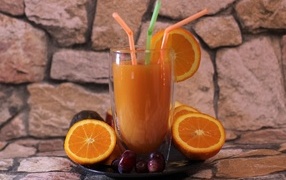 Glass of fresh juice with straws on a table with oranges