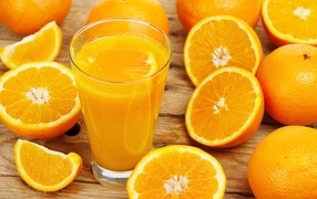 Glass of freshly squeezed juice on the table with orange halves