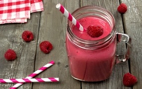 Raspberry smoothie in a glass jar with a straw