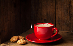 Red cup of coffee on the table with cookies
