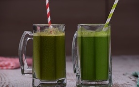 Two glasses of green smoothie with straws