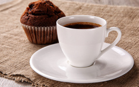 White cup of coffee on the table with cupcake