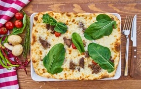 Meat pizza with cheese and green leaves