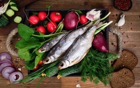 Сушеная рыба на столе с овощами и зеленью 