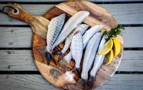 Fresh fish on a board with lemon slices