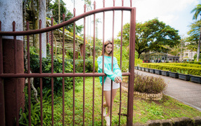 Девушка азиатка стоит у железных ворот 