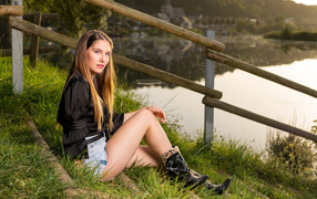 Beautiful girl sitting on the river bank