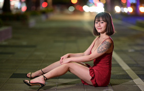 Cute Asian girl in a red dress sitting on the road