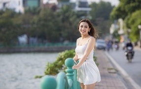 Улыбающаяся девушка азиатка в белом летнем костюме