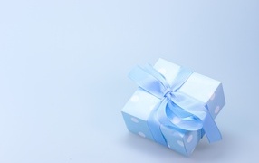 Gift box with blue ribbon on gray background