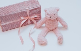 Подарок с розовой игрушкой на сером фоне