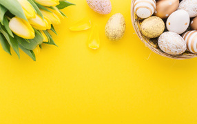 Букет тюльпанов и разноцветные яйца на желтом фоне на Пасху