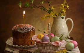 Кулич со свечой и крашеными яйцами на столе на Пасху