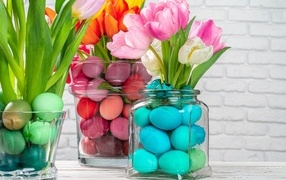Jars with colored eggs and tulips for Easter