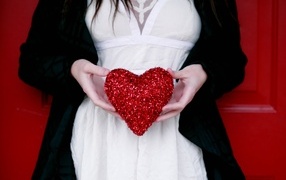Red heart in the hands of the bride