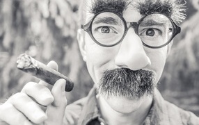 Man with glasses holding a cigar