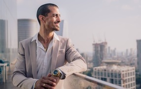 Smiling stylish man in suit standing on balcony