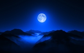 Big moon in the night sky over the mountains