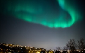 Green aurora in the sky over the night city