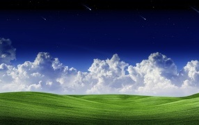 White clouds in the blue sky over a green field