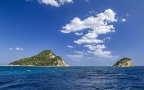 Mountains covered with greenery in the sea under the blue sky