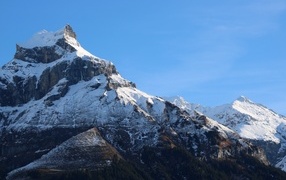 The top of the mountain is covered with snow in the rays of the sun