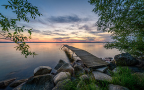 Old wooden pier by the lake at sunset